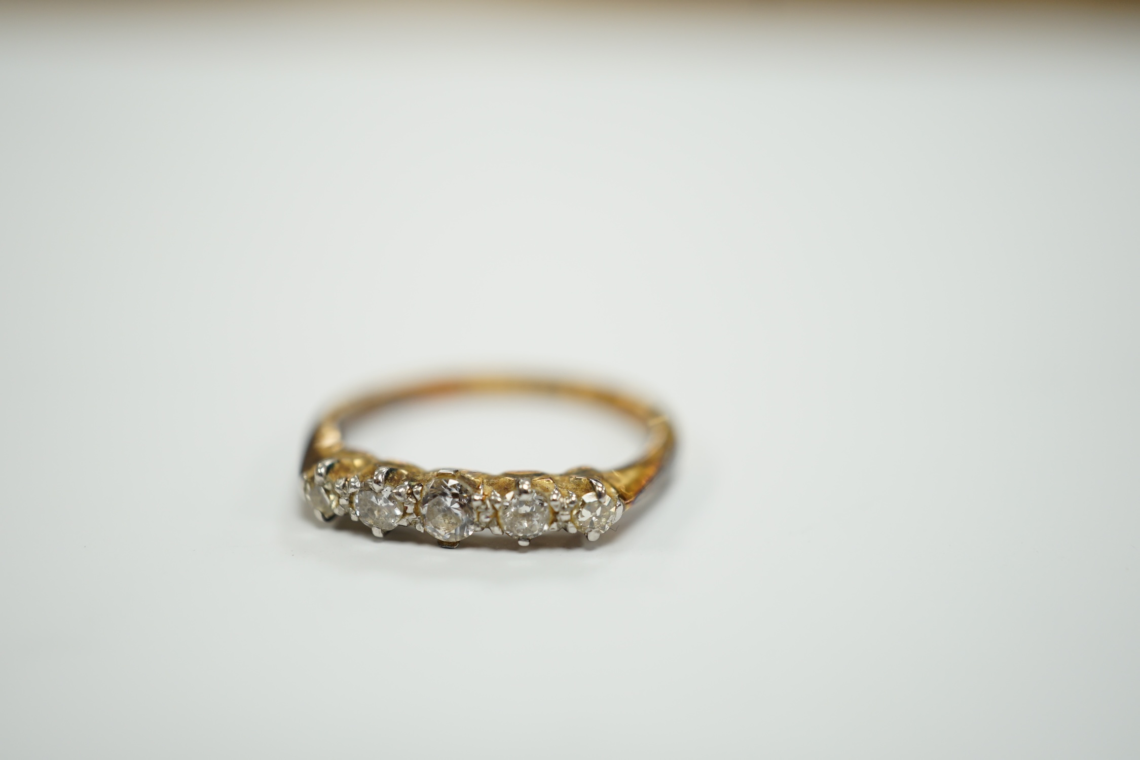 An early 20th century 18ct, plat and graduated five stone diamond chip set half hoop ring, size H, gross weight 2.2 grams.